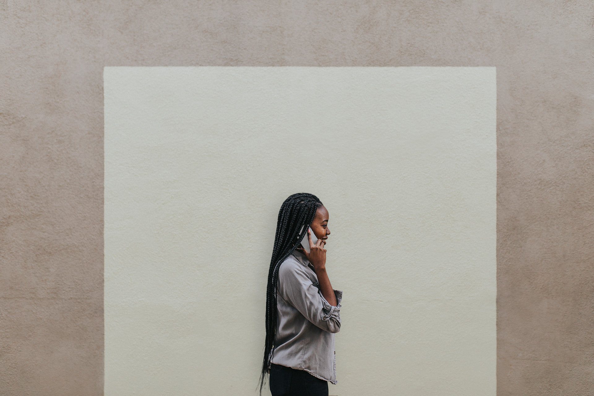 black woman on the phone against a white wall